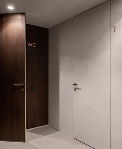 Modern minimalist interior design with a combination of white doors with black handles, concrete walls, and wooden materials.