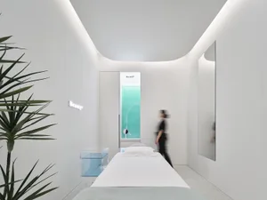 A modern minimalist beauty therapy room with white walls and furniture.