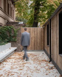 A minimalist pathway with concrete flooring and fallen autumn leaves.