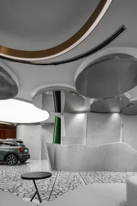 Modern car showroom interior with metallic ceiling elements and large circular lights.