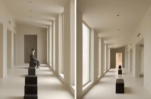A minimalist hall with white columns and large windows.
