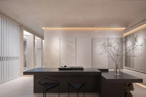 Modern minimalist kitchen with a large island, black stools, and concrete finishes.