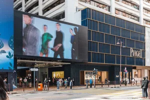 A modern commercial building featuring a large digital billboard displaying a fashion show with models wearing stylish clothi