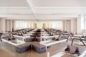 An empty, minimalist indoor fitness center featuring solid-wood flooring andbenches.
