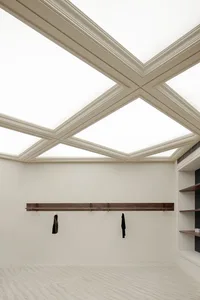 A spacious, modern interior with a unique triangulated ceiling design, featuring abundant natural light.