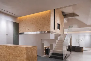 A modern office interior featuring concrete walls and a glass staircase.