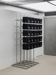 極簡金屬音響展示，由多個揚聲器以格狀排列於金屬支架上，置於昏暗環境中