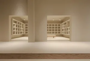 An empty minimalist interior space with concrete walls and wooden shelves.