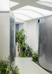 A modern hallway with dark metallic walls featuring lush green plant walls