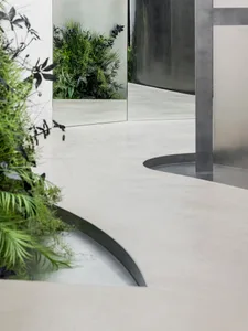 Modern industrial office space featuring a concrete floor, mirrored wall, and metal structural elements.