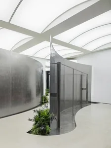 A modern interior design featuring a metallic corridor with green plants and a curved wall.