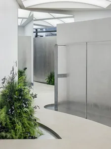 A modern interior design featuring a plant-lit corridor with glass walls and mirrors.