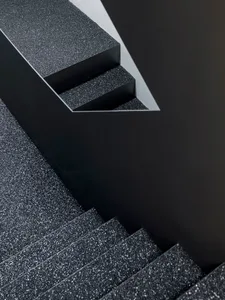A close-up of a black granite staircase with textured steps and a contrasting wall.