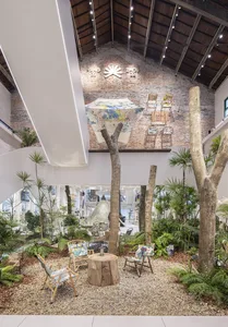 An industrial retail space featuring natural wood and brick materials, with green plants and a large umbrella display.