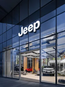 Modern automobile storefront with glass, concrete, and lighting features.