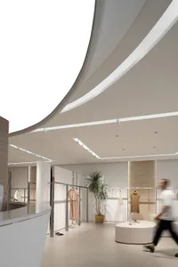 現代服飾店室內，地面擺放玻璃盆栽，旁邊有植物與人行道相鄰。