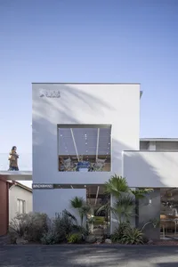 Modern retail storefront with white-rendered and concrete materials, large open window showcasing interior.