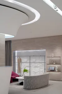 A modern storefront with a minimalist design featuring white walls, curved glass, and a curved seating area.