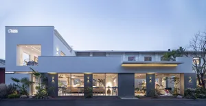 A modern storefront with a concrete facade and large windows, featuring a white and gray color palette.