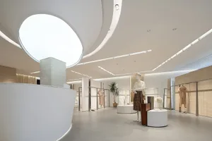 A modern interior of a clothing store featuring white marble materials and minimalist design.