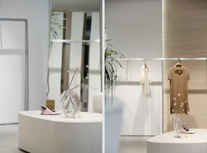 Modern retail store with minimalist design, featuring clothing racks and decorative elements.