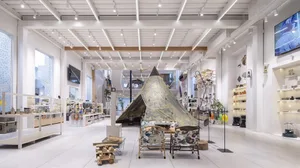 A spacious retail store with modern design elements, featuring a teepee-shaped tent and a variety of products on display.