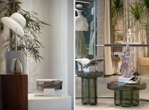 Glass and metal display tables with fashion accessories and dresses in the background.