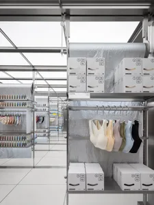 Retail store with metal shelves displaying clothing products, boxes of products, and hangers.