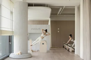 簡約健身房採用中性色調，設有女性在reformer機上運動的畫面。