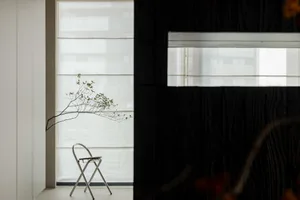 A minimalist bedroom with a modern metal chair and minimalist decor.
