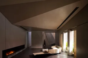 A modern residential interior with concrete walls, a circular sofa, and a fireplace.