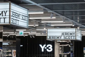 A retail space with illuminated signage featuring the name Jeremy Scott and Y-3, showcasing modern lighting design.