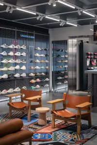 A retail interior featuring a metal grid display wall showcasing various styles of shoes in a store.
