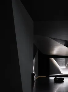 A modern black interior space with concrete walls and surfaces, featuring minimalist design and geometric shapes.