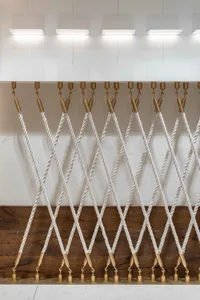 Textile cords suspended from brass hooks in a modern lighting exhibition setting.