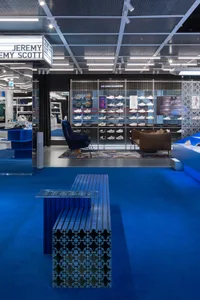 Modern retail space showcasing a collection of shoes with metal grating, glass walls, and concrete flooring.