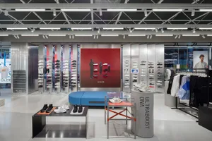 Modern retail store interior featuring a white footwear display with glass cabinets and metal racks.