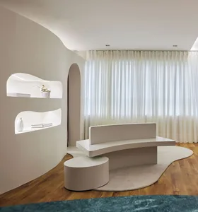 A modern white living room with curved furniture, minimalistic design, and white curtains.