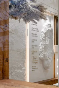 Interior space with raw concrete walls, abstract lighting, and natural elements.