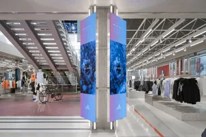 A modern sportswear retail store with glass walls and digital signage.