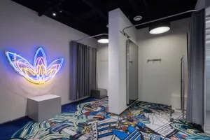 A well-designed retail shop with a concrete floor and illuminated neon art on the walls.