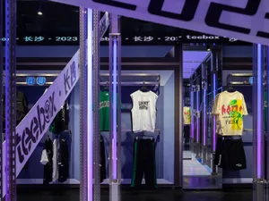 Modern retail interior with clothing shop front displaying various garments and accessories, highlighted by metallic poles an