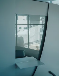 A minimalist chatroom interior with a modern window design, white walls, and metallic accents.