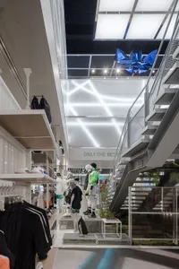 A minimalist retail store interior featuring metal shelves, glass windows, and concrete flooring.