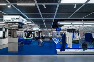 A modern retail interior featuring blue shoes and white clothing on display.