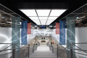 Modern interior of a shopping mall featuring metallic and glass elements with light accents.