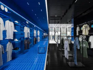 零售空間內有藍色瓷磚牆面與黑色金屬裝置，展示服裝商品。