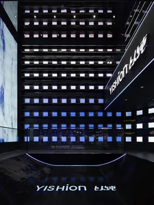 A modern shopping center interior featuring glass walls and bright neon lighting.