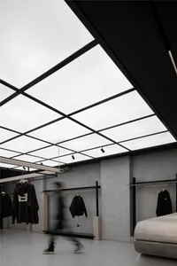 A modern clothing store features sleek concrete elements and a large glass ceiling.