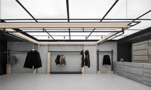 A minimalist retail shop with concrete walls, black metal hangars, and hanging clothing.